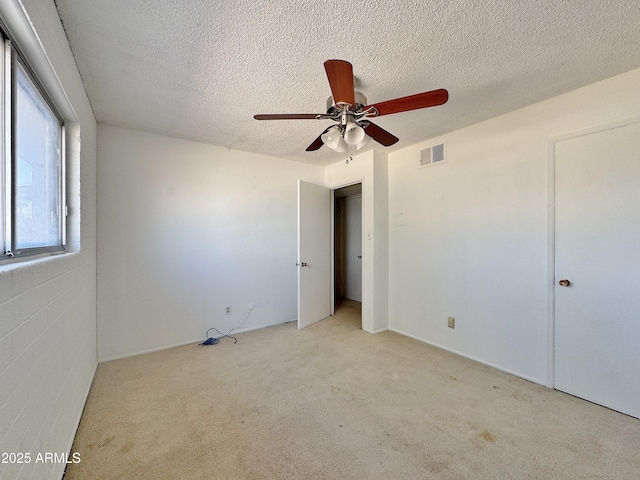 unfurnished bedroom featuring ceiling fan, light colored carpet, and a textured ceiling