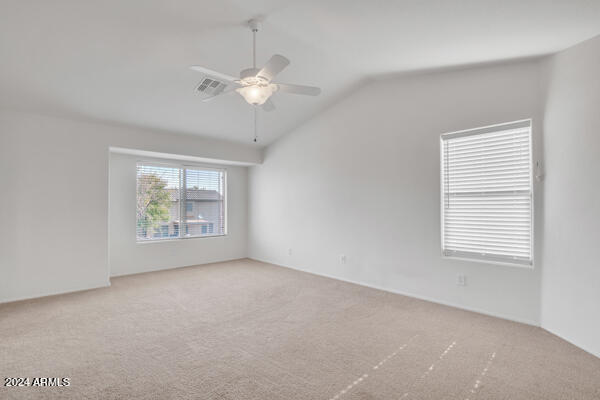 carpeted spare room with ceiling fan and vaulted ceiling