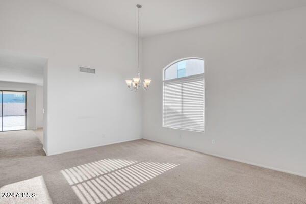 carpeted spare room with a notable chandelier