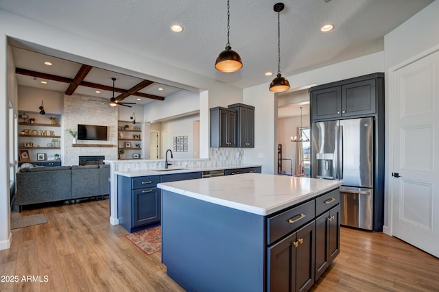 kitchen with stainless steel fridge, coffered ceiling, a center island, light wood-type flooring, and a sink