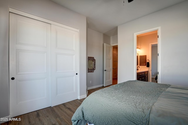 bedroom with a sink, dark wood finished floors, baseboards, a closet, and ensuite bath