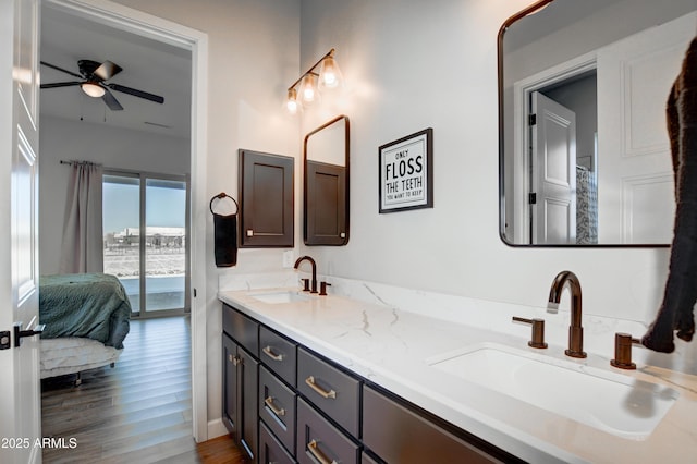 ensuite bathroom with double vanity, a sink, ensuite bath, and wood finished floors