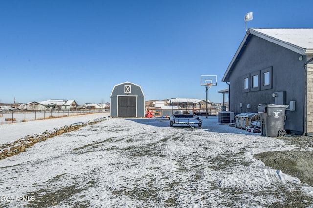 exterior space with a storage shed, central AC unit, an outbuilding, fence, and stucco siding