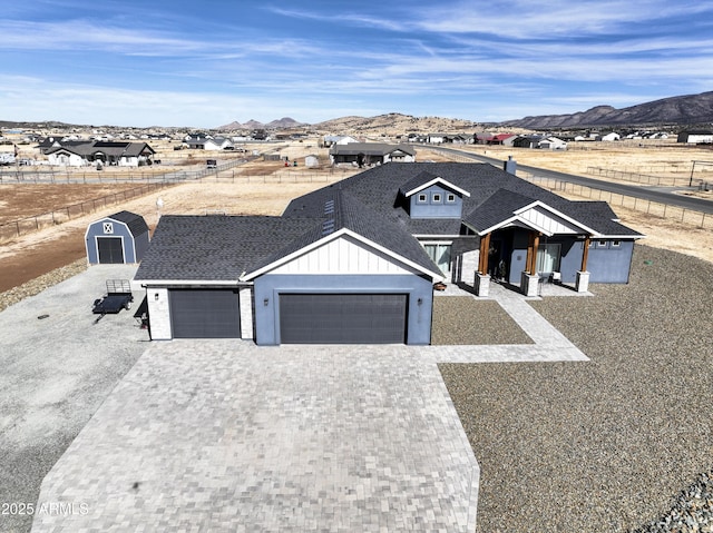 view of front of home featuring a mountain view, fence, roof with shingles, decorative driveway, and board and batten siding