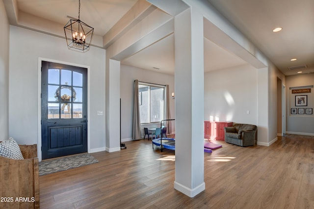 foyer entrance featuring a notable chandelier, baseboards, wood finished floors, and recessed lighting