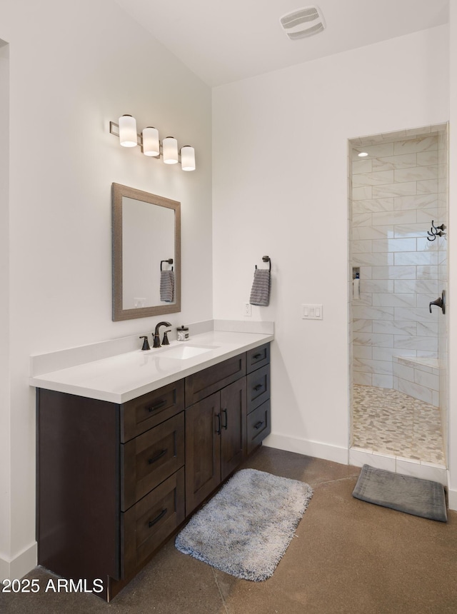 full bath with visible vents, baseboards, vanity, and a tile shower