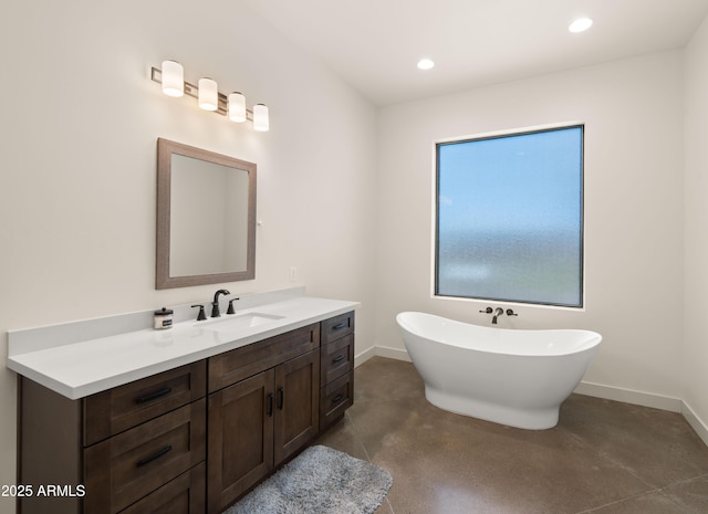 bathroom featuring recessed lighting, a freestanding tub, baseboards, and vanity