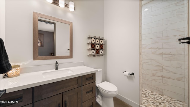 full bath with tiled shower, toilet, vanity, and baseboards