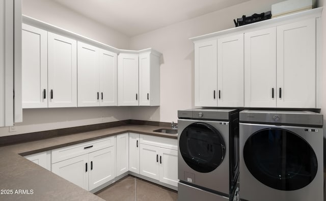 clothes washing area with a sink, cabinet space, washing machine and dryer, and tile patterned floors