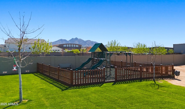 view of jungle gym featuring a yard, a mountain view, and fence