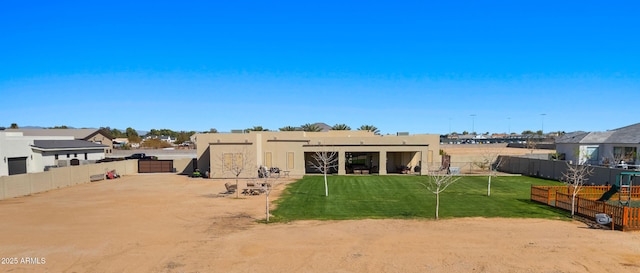 rear view of house with a fenced backyard, a lawn, and stucco siding