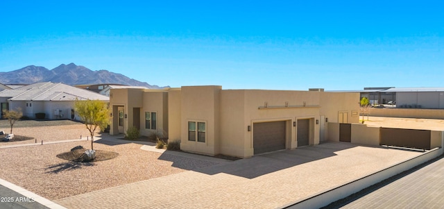 southwest-style home featuring concrete driveway, a mountain view, a garage, and stucco siding