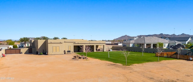 back of house with a yard, a mountain view, stucco siding, and fence