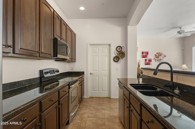 kitchen with sink, stainless steel appliances, dark stone countertops, and light tile patterned floors