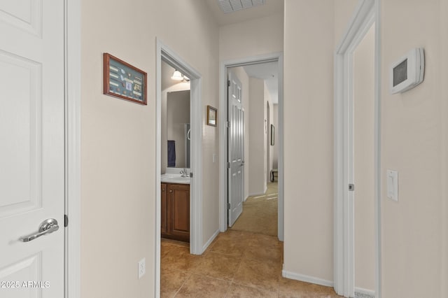 hall featuring sink and light tile patterned floors