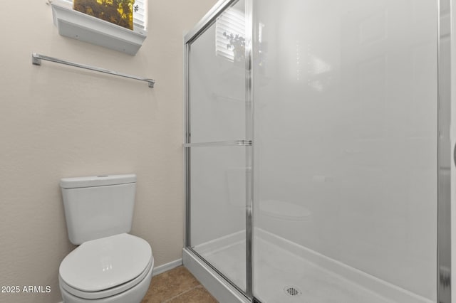 bathroom featuring toilet, a shower with door, and tile patterned flooring