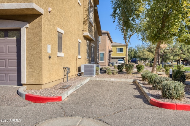 view of side of home featuring a garage and central AC