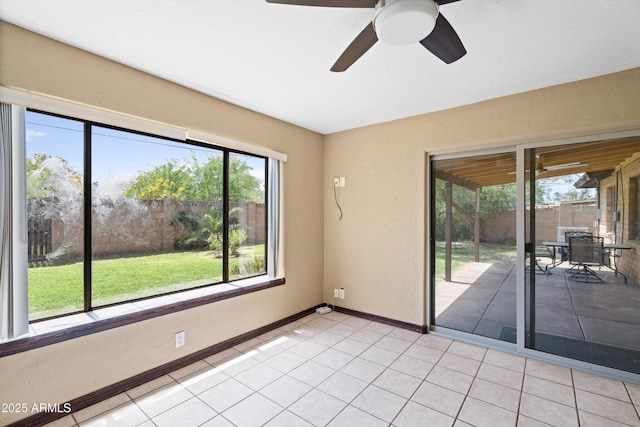 empty room with light tile patterned floors, a ceiling fan, and baseboards