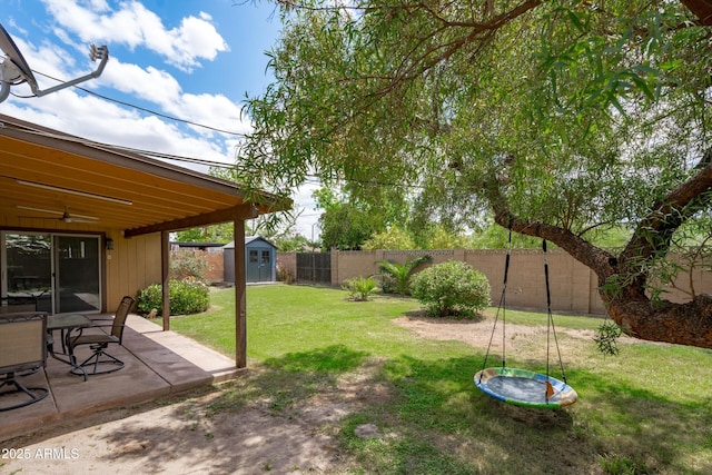 view of yard featuring a patio area, an outdoor structure, ceiling fan, a fenced backyard, and a storage unit