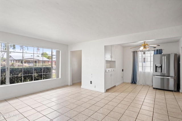 unfurnished living room featuring light tile patterned floors, ceiling fan, and baseboards