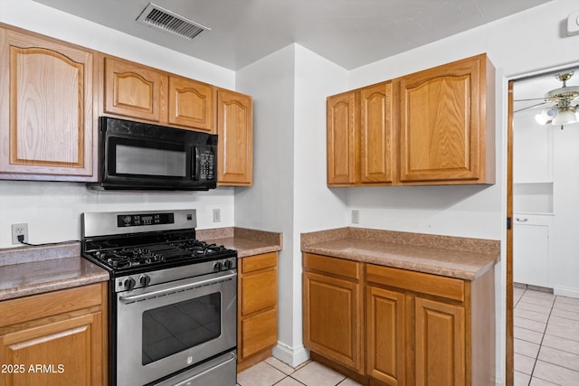 kitchen with light tile patterned floors, black microwave, ceiling fan, visible vents, and stainless steel gas range oven