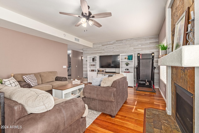 living room with built in features, ceiling fan, and light hardwood / wood-style flooring