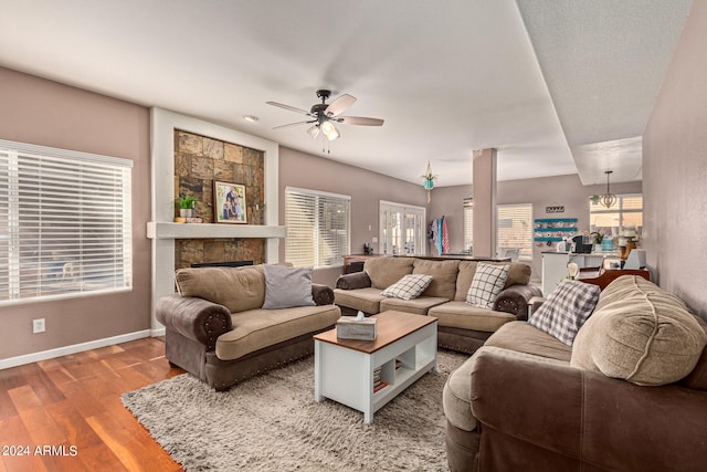 living room with a fireplace, wood-type flooring, and ceiling fan