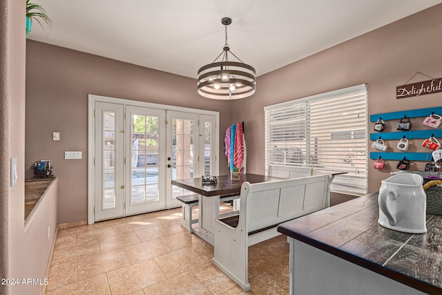 kitchen with pendant lighting, light tile patterned floors, a notable chandelier, and french doors