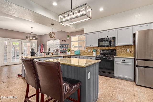 kitchen with plenty of natural light, black appliances, a breakfast bar area, and decorative light fixtures