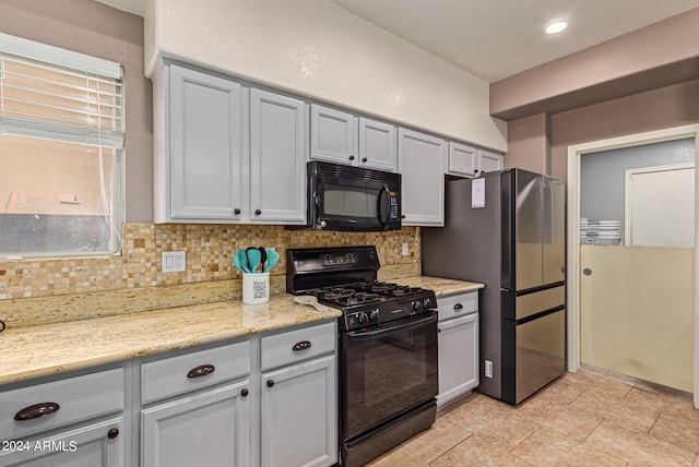 kitchen with black appliances, light stone counters, decorative backsplash, and light tile patterned flooring