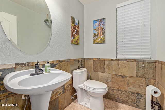 bathroom with tile walls, toilet, and tile patterned flooring