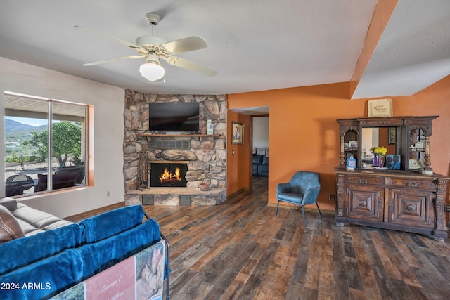 living room with a textured ceiling, dark wood-type flooring, a fireplace, and ceiling fan