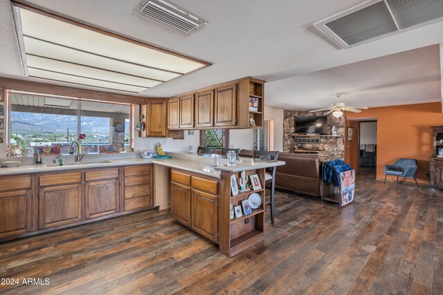 kitchen featuring sink, dark wood-type flooring, kitchen peninsula, and a fireplace