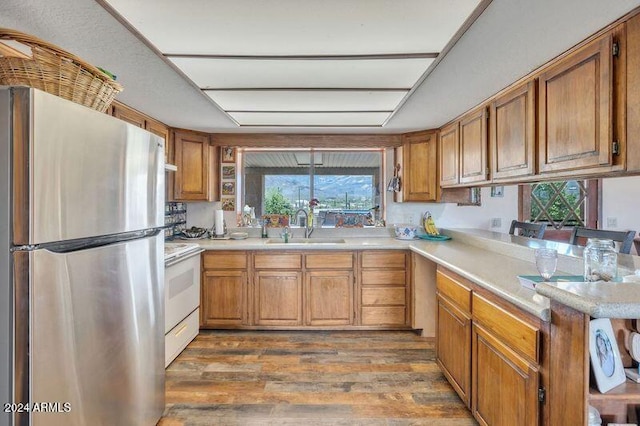 kitchen with sink, dark hardwood / wood-style flooring, white range, and stainless steel fridge