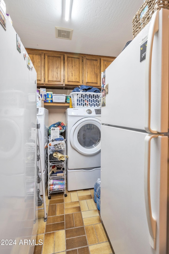 laundry area with a textured ceiling and washing machine and clothes dryer