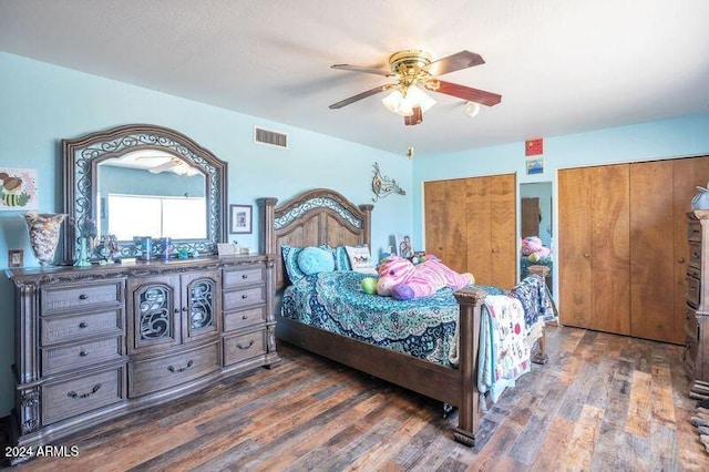 bedroom with dark hardwood / wood-style floors, two closets, and ceiling fan