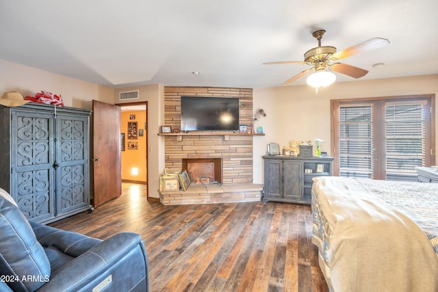 bedroom featuring dark wood-type flooring, ceiling fan, and a fireplace