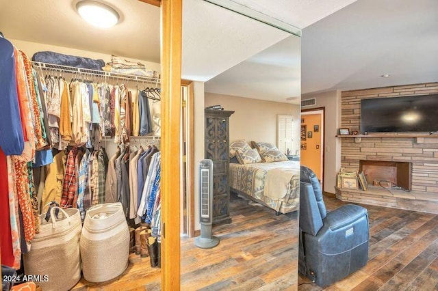 bedroom with hardwood / wood-style floors, a stone fireplace, and a closet