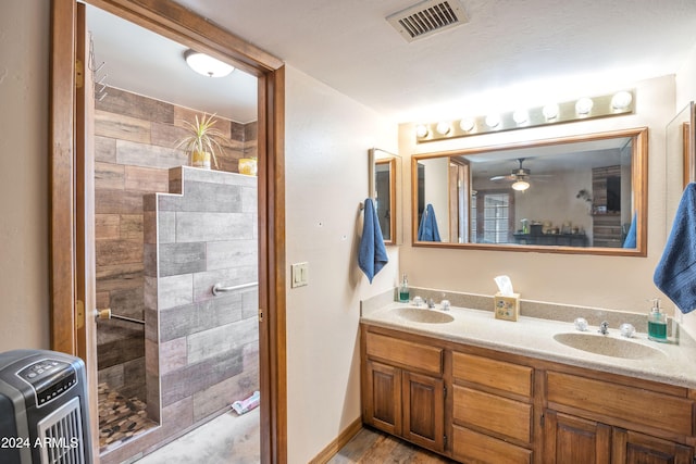 bathroom featuring a tile shower, hardwood / wood-style floors, vanity, and ceiling fan