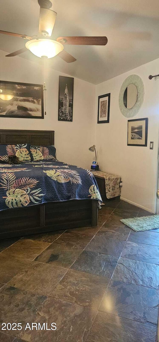 bedroom featuring ceiling fan and stone finish flooring