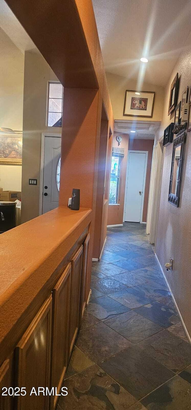 hall with stone tile floors and baseboards