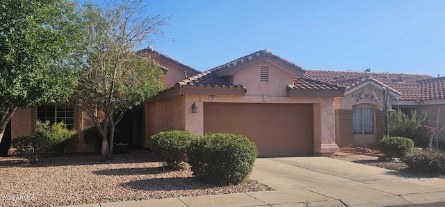 mediterranean / spanish home with an attached garage, driveway, a tile roof, and stucco siding