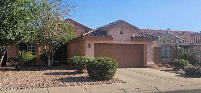 mediterranean / spanish house with a garage, stucco siding, driveway, and a tile roof
