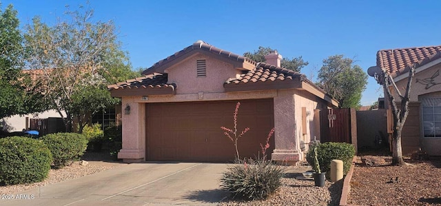 view of front of property with a tiled roof, fence, concrete driveway, an attached garage, and stucco siding