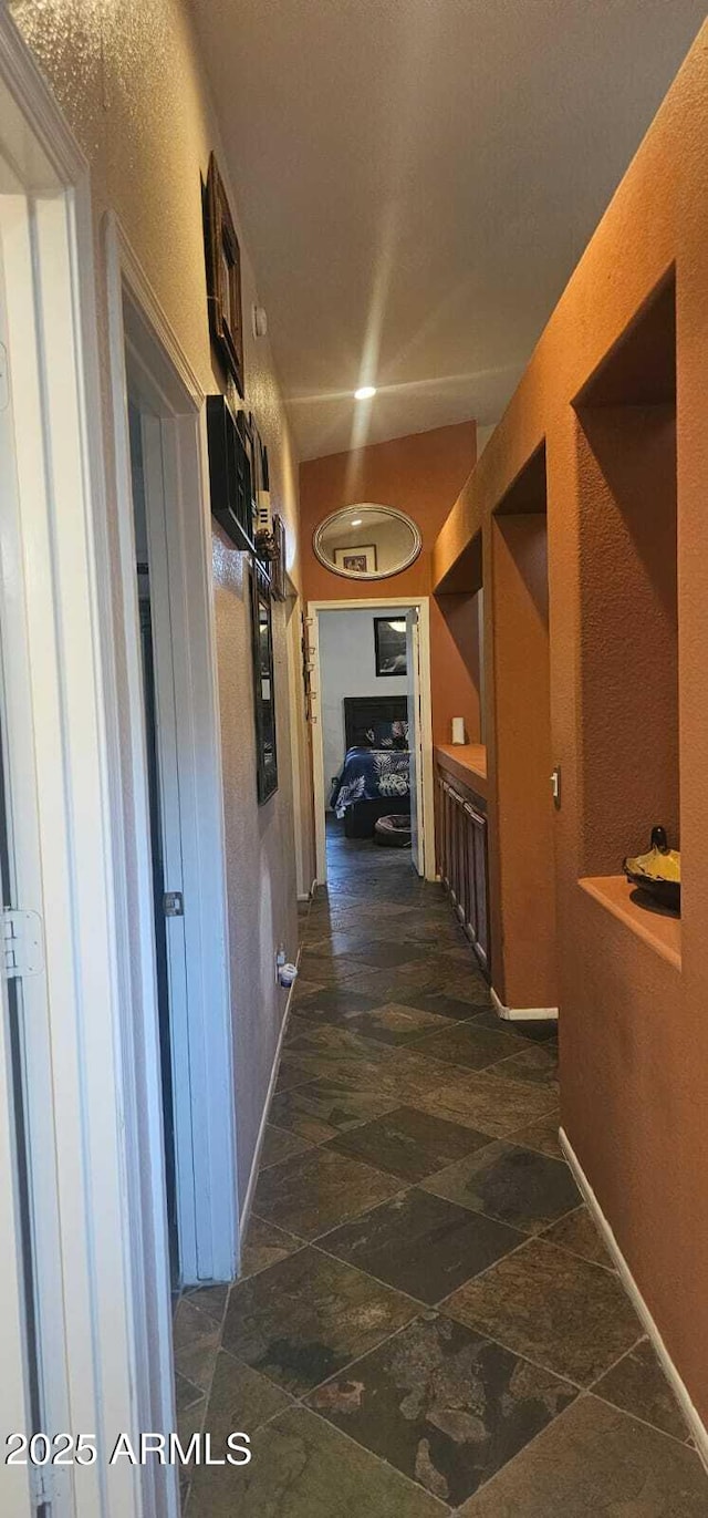 hall featuring baseboards and stone finish floor