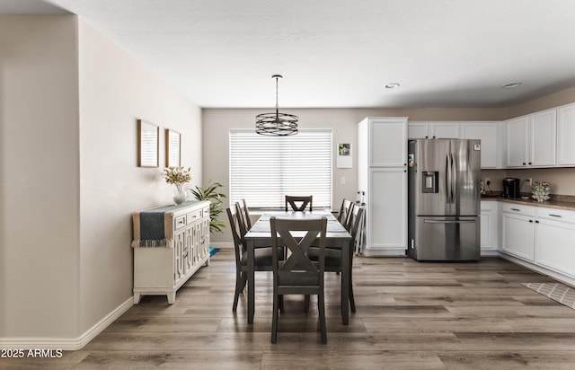dining space featuring an inviting chandelier, light wood-type flooring, and baseboards