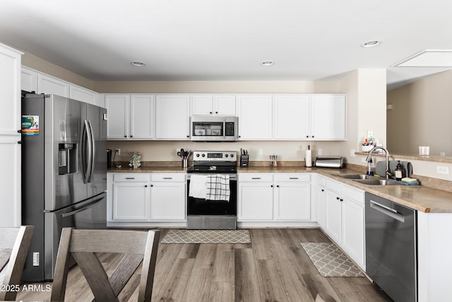 kitchen featuring a sink, white cabinets, light wood-type flooring, and stainless steel appliances