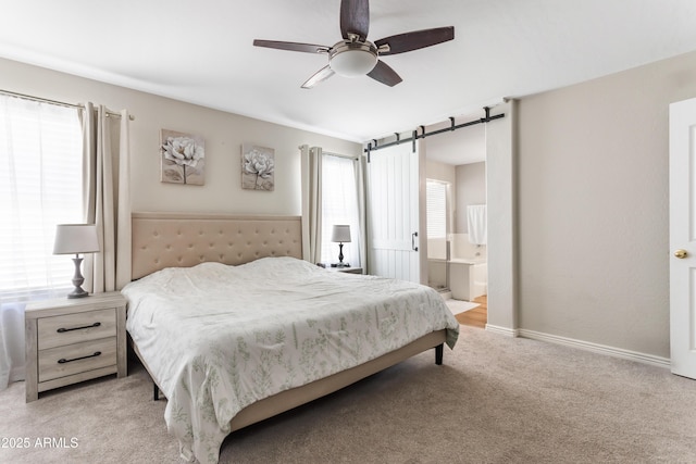 bedroom with baseboards, a barn door, a ceiling fan, connected bathroom, and light carpet