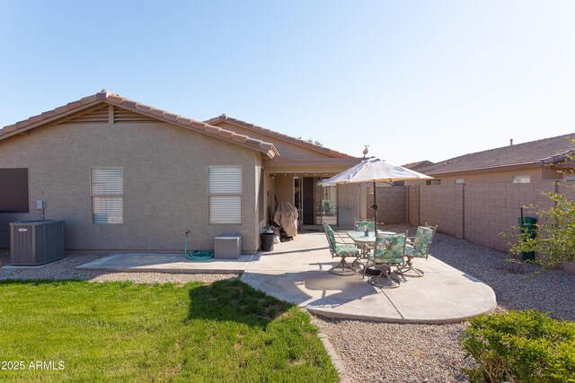 back of house featuring central AC, a yard, stucco siding, a patio, and fence