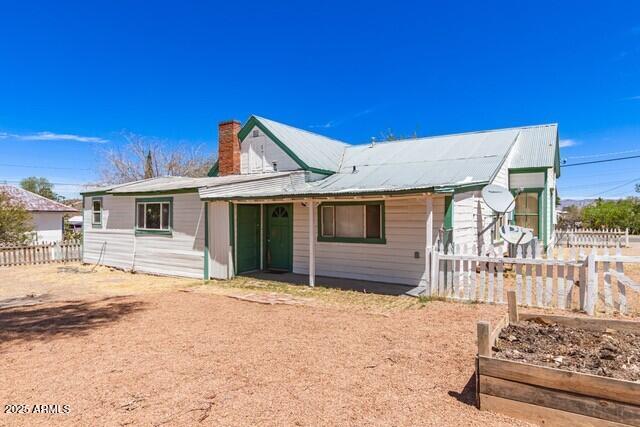 101 E Safford St, Tombstone, AZ 85638 - view of front of home featuring a chimney, fence, metal roof, and a garden